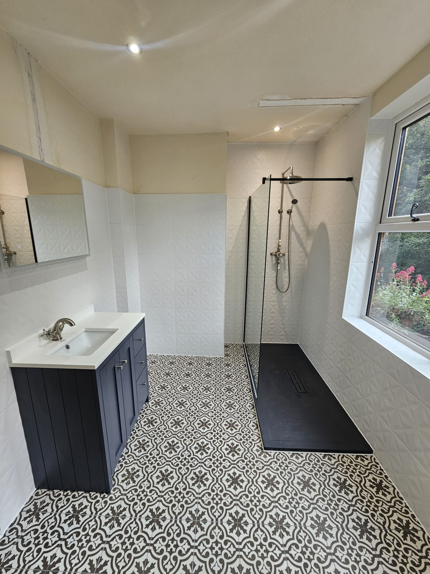 Patterned floor wet room with navy vanity, linear drain and black shower tray installed by Blue Sky
