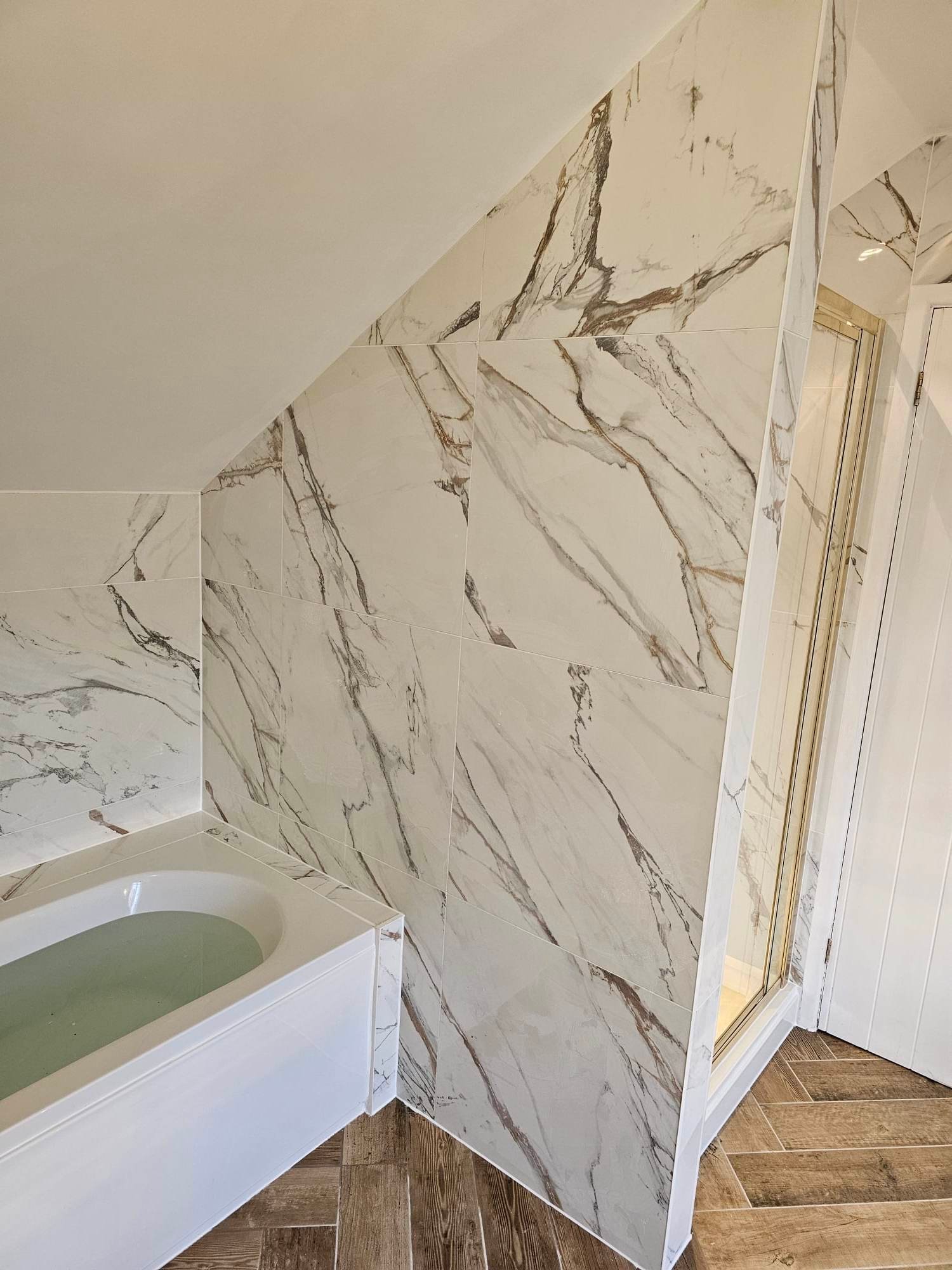 Marble-effect large-format wall tiling around a fitted bath in Tamworth