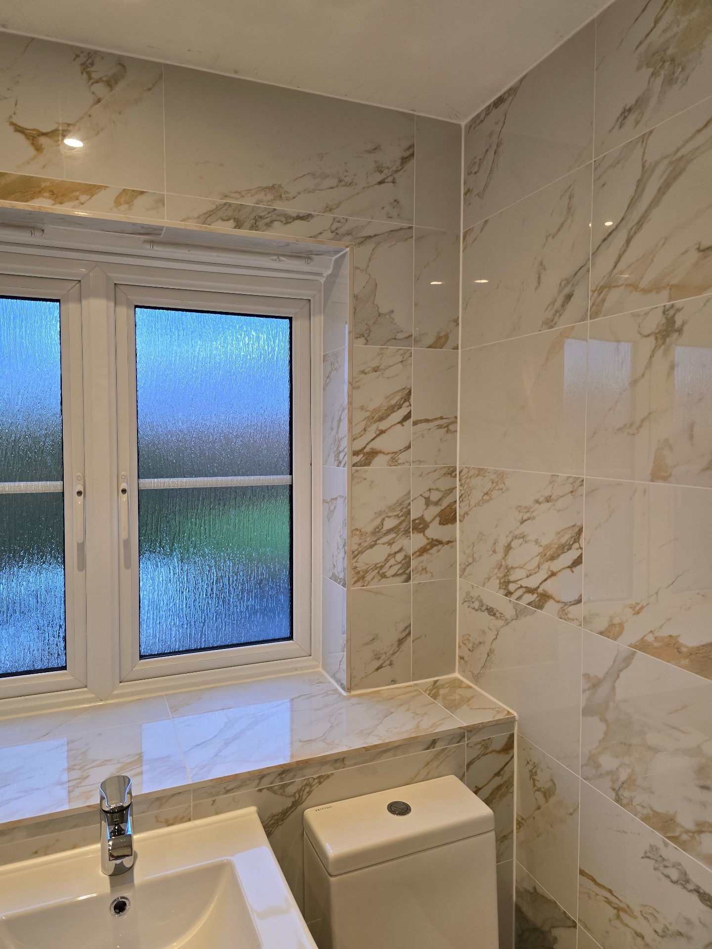 Marble-effect wall tiling with mitred window reveal in a Tamworth bathroom