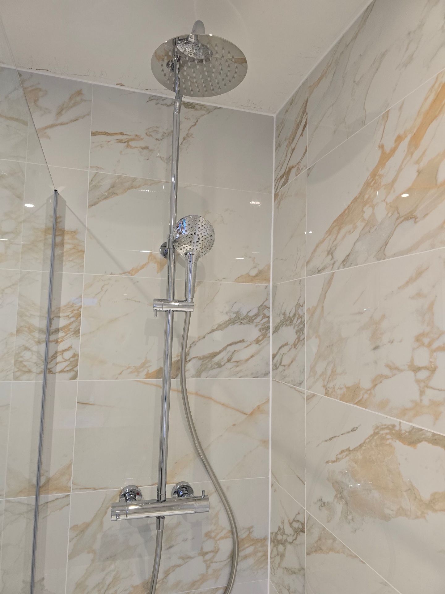 Chrome thermostatic shower riser rail installed against marble-effect tiles in Tamworth