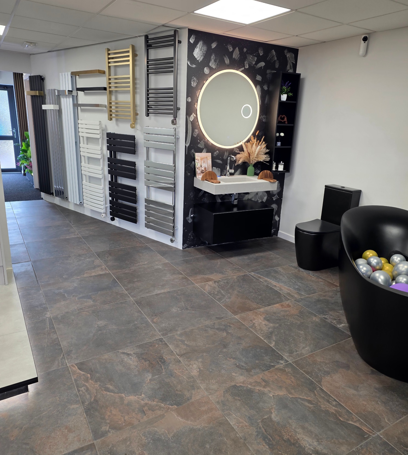 Wall-hung vanity with bold dark feature wall and illuminated round mirror at the Tamworth showroom